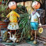 Free Spanish Masculine & Feminine two cartoon dolls of a girl and boy holding flowers and a white swan in front